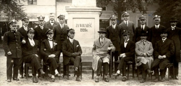 Członkowie Związku Weteranów pod pomnikiem na Rynku w Święciechowie. Czwarty z lewej (bez czapki) stoi  Władysław Kędziora. Czwarty z lewej (w kapeluszu) siedzi burmistrz Jan Matyla, a obok niego piąty od lewej Jan Kalitka.