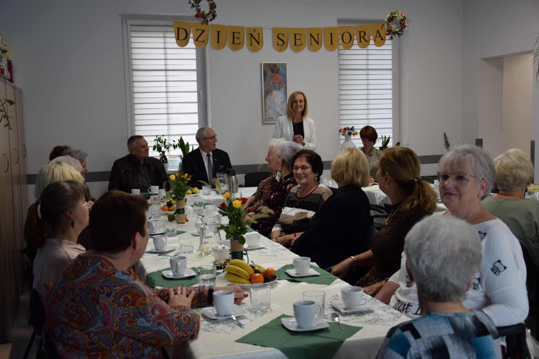 Zdjęcie przedstawia zgromadzonych seniorów przy stole wraz z opiekunami oraz wójtem gminy wraz z przewodniczącym rady&nbsp;
