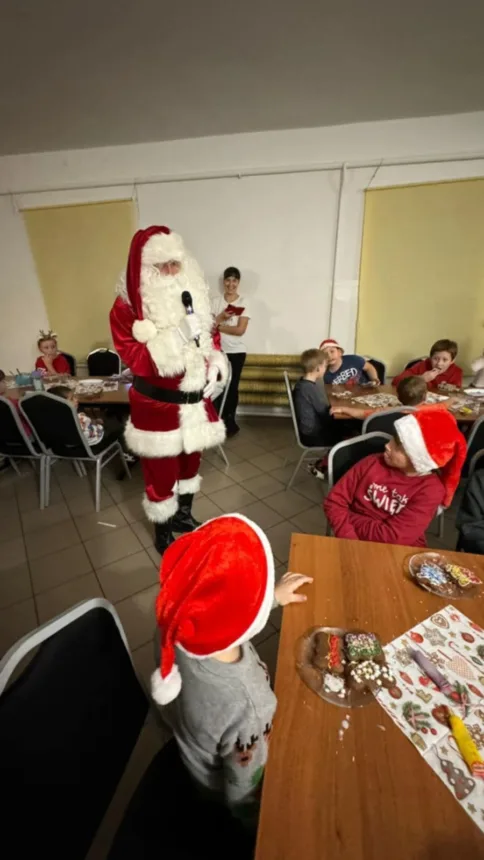 Zdjęcie Świętego Mikołaja który w ręce trzyma mikrofon i przemawia do dzieci