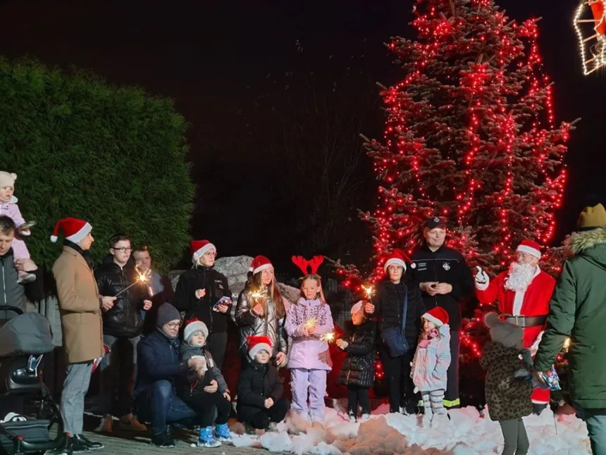 Zdjęcie uczestników wydarzenia przy oświetlonej choince